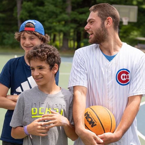 3 boys standing on basketball court at overnight camp
